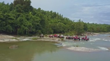 insanlar quadricycles güçlü nehir boyunca sür.
