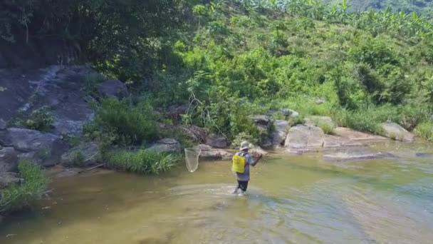 Hombre con caña de pescar camina a lo largo del río — Vídeos de Stock