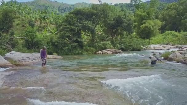 Pescador llevando red con pescado capturado a través del río — Vídeos de Stock