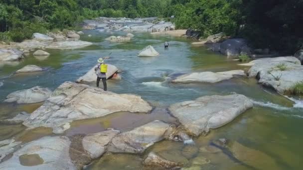 Uomo a piedi e la pesca in fiume di montagna — Video Stock