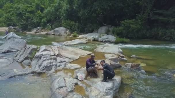 Mannen zittend op de rotsen en zetten gevangen vis — Stockvideo