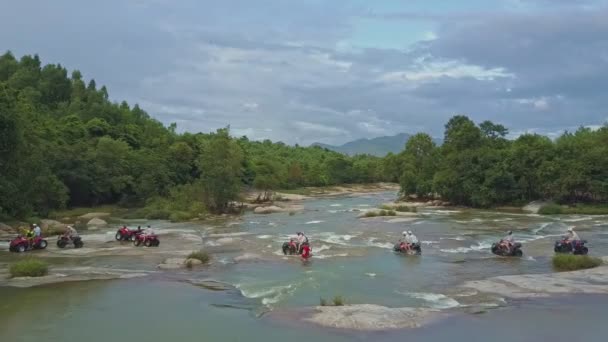 Les gens conduisent des quadricycles le long d'une rivière puissante — Video
