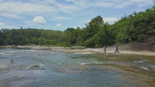 Мужчины, пересекающие мелководную реку — стоковое видео