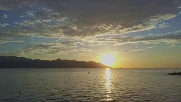 Sonnenaufgang über dem ruhigen Ozean gegen ferne Hügel — Stockvideo