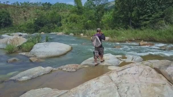 Хлопці сидять на плоских камінь серед річка — стокове відео