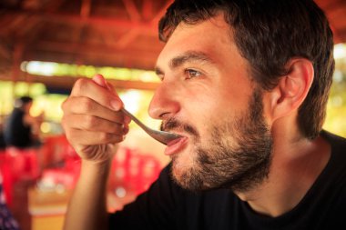 Tablo-kaşık Cafe çiçekli arka plan ile siyah t-shirt closeup sakallı adam yiyor