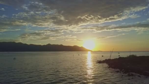 Salida del sol sobre el océano tranquilo contra colinas distantes — Vídeo de stock