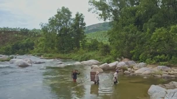Pessoas com cestas cruzando rio raso — Vídeo de Stock
