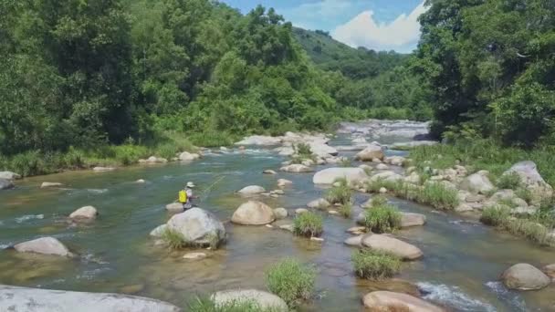 Man with fishing rod walks along river — Stock Video