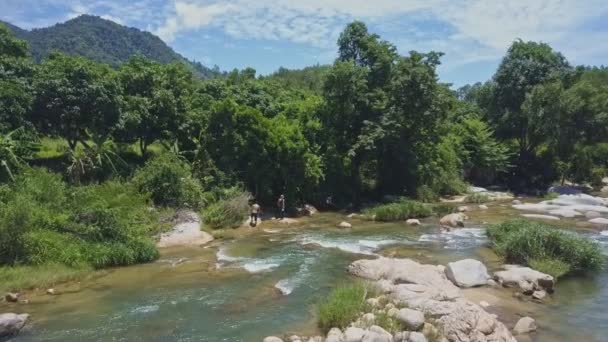 Парни идут по большим камням возле реки — стоковое видео