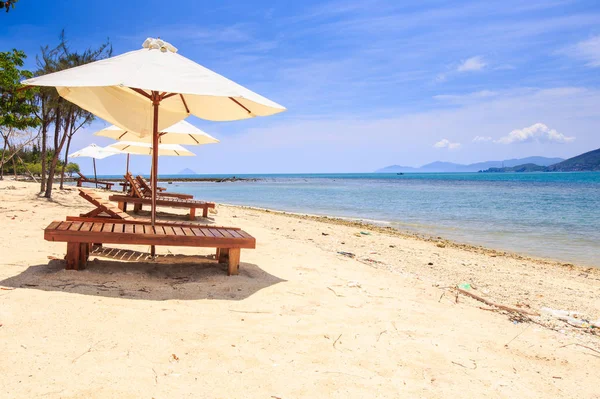 Sillas bajo paraguas en la playa de arena por mar — Foto de Stock