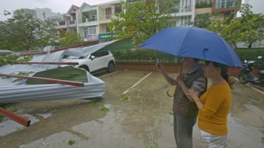 Nhatrang /Vietnam - 04 Kasım 2017: Mavi şemsiye almak Fotoğraflar altında yerel halkın çatılar otomobiller üzerinde Damrey kasırga üzerinde Kasım 04, Nhatrang sonra kırık
