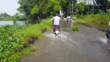 Hoi bir / Vietnam - 15 Ekim 2017: arka görünümü adam kask içinde sürücüler motosiklet River 15 Ekim'de Hoi tropik bitkiler arasında sular altında yol boyunca bir