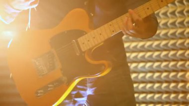 koyu mavi giysili tatlı adam duvara sahne ışıkları ve soffits altında elektrik gitar çalıyor