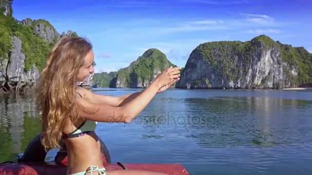 性感的金发碧眼的长发女孩在比基尼使自拍对梦幻般的公顷长湾美丽的岩石群岛船板 — 图库视频影像