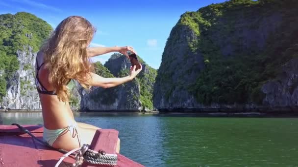 水着でのセクシーな女の子を薄い裏面表示 Selfie 湾に対してスマート フォンでは 岩の島風揺れる長い髪 — ストック動画