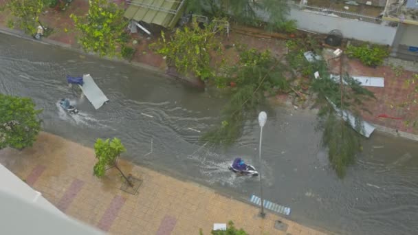 車を人がスクーターと台風の影響を受ける建物の間浸水通り沿い屋根部分を引っ張る男 — ストック動画