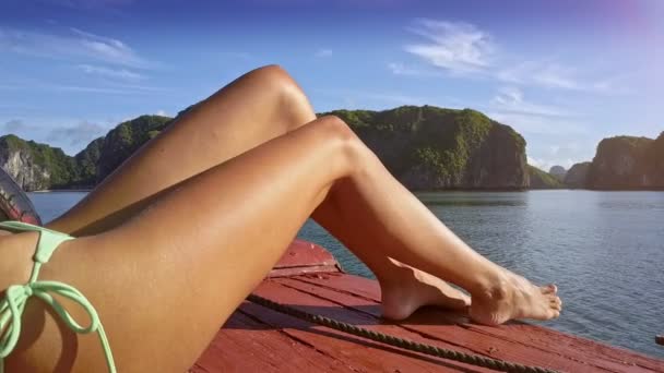 アジアのクローズ アップ長いセクシーな女の子の脚ボートの大きい山に対してかなり紺碧湾でセーリング — ストック動画