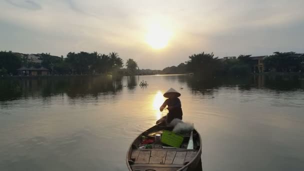 Hombre se sienta en barco sosteniendo redes de pesca contra la salida del sol — Vídeos de Stock