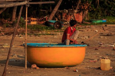MUI KD/Vietnam - 17 Mart 2016: kırmızı t-shirt Asyalı çocuk oturur turuncu teknede yuvarlak kum plaj güneşli bahar gününde Vietnam'da 17 Mart MUI Ne içinde