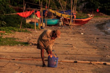 MUI KD/Vietnam - 17 Mart 2016: Asya adam 17 Mart MUI Ne içinde mavi sepet şeylerle balıkçı tekneleri Vietnam karşı deniz plaj aşağı bükülmüş