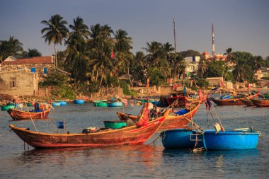 MUI KD/Vietnam - 17 Mart 2016: ahşap yuvarlak ve uzun balıkçı tekneleri float Yalı palmiye ağaçları ve Binalar Vietnam ile karşı deniz yüzeyi Tarih 17 Mart MUI Ne içinde