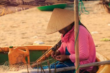 MUI KD/Vietnam - 17 Mart 2016: geleneksel şapka ve pembe bluz Vietnamca kadın yuvarlak teknede oturur ve düzgünce Balık ağı plaj üzerinde Mart 17, MUI Ne örgüleri
