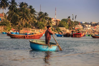 MUI KD/Vietnam - 17 Mart 2016: Asya çocuk satırları mavi yuvarlak büyük tekneler ve palmiye ağaçları ve Binalar ile Sahil karşı denizde balıkçı teknesi 17 Mart MUI Ne içinde