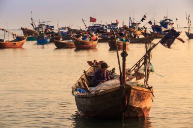 MUI KD/Vietnam - 17 Mart 2016: Asya balıkçı oturur diğer tekneler ve berrak gökyüzü karşı farklı olta ile büyük tekne günbatımında 17 Mart MUI Ne içinde