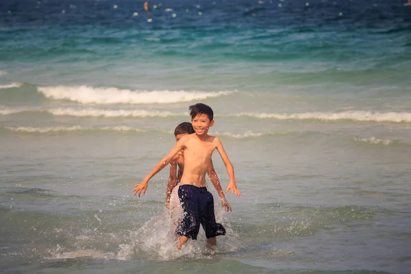 Nha Trang/Vietnam - 16 Nisan 2017: mutlu gülümseyen Vietnamlı çocuk oyun olarak okyanus dalgalarının masmavi suya karşı sahilde sıcak güneşli 16 Nisan Nha Trang içinde
