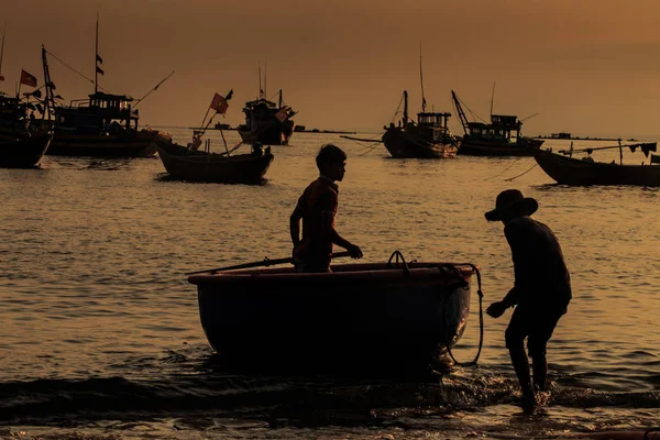 MUI KD/Vietnam - 17 Mart 2016: eski balıkçı tarafından standları tekne ve çocuk siluetleri uzun tekneler siluetleri karşı deniz plaj üzerinde yuvarlak gün batımı gün batımında 17 Mart MUI Ne içinde