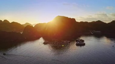 Drone karanlık dağlık ada siluet manzarası parlak gündoğumu ve sakin okyanus bay karşı ön plan üzerinde güneş doğarken gösterir