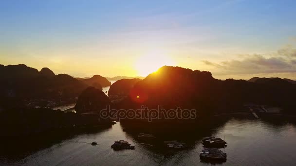 空撮明るい太陽ディスクは静かな海湾上熱帯日の出暗い岩の島の後ろから出現します — ストック動画