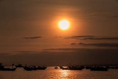 gün batımında tekne siluetleri balıkçılık ile Okyanusu üzerinden karanlık gökyüzünde bulutlar büyük portakal güneş diski