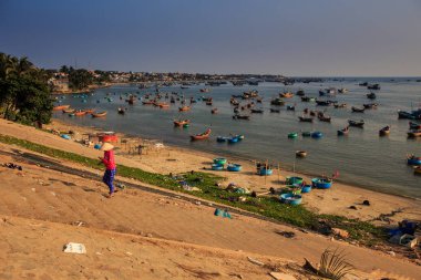 Vietnamca kişi karşı balıkçı tekneleri sahilde denize sıfır yamacında şapka ve gün batımında masmavi deniz