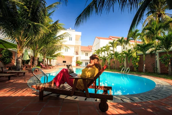 uzun saçlı sarışın kız otel yüzme havuzunda defter ile avuç içi gölgede koltuk katlama oturur