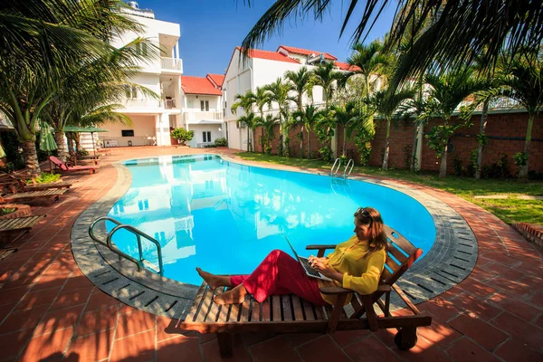 Sarı uzun kollu bluz genç kadın defter sandalyeyle katlama rahatlatır ve otel evler havuza yansıtacak