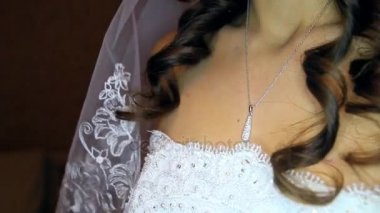 Açık dekolte beyaz gelinlik içinde closeup uzun saçlı esmer gelin tören için hazırlanıyor boynundaki kolye dokunur
