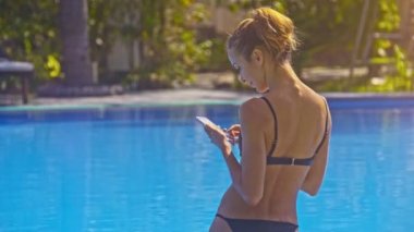 büyük boş su havuzu mavi su ile karşı arka görünümü genç kadın telefon ile siyah Bikini durumda