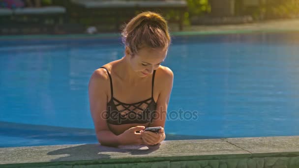 Chica Rubia Bastante Delgada Mira Través Teléfono Inteligente Moderno Piscina — Vídeos de Stock