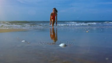 genç kız mavi gökyüzü altında resimsel okyanus tarafından yıkanmış kum üzerinde yoga poz Virabhadrasana tutar