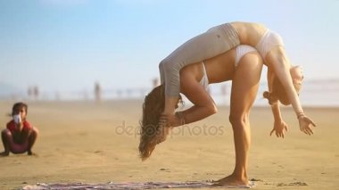 Goa, Hindistan - 09 Aralık 2012: tatlı çift yoga holding kızın arkasında deniz manzarası karşı ıssız sahilde Goa içinde Aralık ayı 09 işi kadın küçük Hintli çocuk bakar