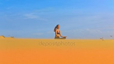 yoga lotus pozisyonu altın kum ve sınırsız mavi gökyüzü arasında şaşırtıcı görünümü sarışın uzun saçlı kız oturuyor