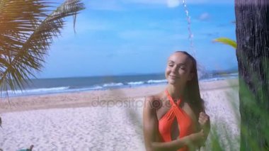 Turuncu mayo güzel uzun saçlı kız closeup kum resimsel okyanus karşı tatlı su duş alır