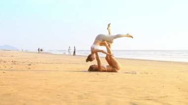 Goa, Hindistan - 09 Aralık 2012: Çok ince kız akrobatik yoga poz Değiştir pozisyon gerçekleştirmek yere düşüp gülmek plaj boyunca 09 Aralık Goa içinde insanlar karşı