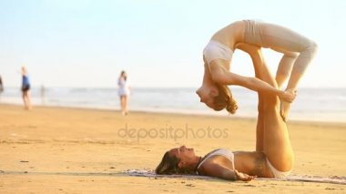 Goa, Hindistan - 09 Aralık 2012: Yan görünümü ışık saçlı kız tutar ortak turistler sakin deniz 09 Aralık Goa içinde yürüyüş karşı yoga egzersiz gerçekleştirme bacaklar tarafından