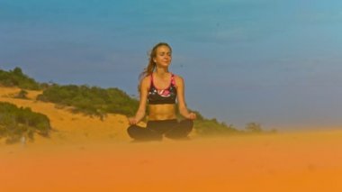 güzel sarışın kız siyah pembe top at kuyruğu ile yoga lotus poz sınırsız mavi gökyüzü karşı kabuklarıyla altın rahatlatır
