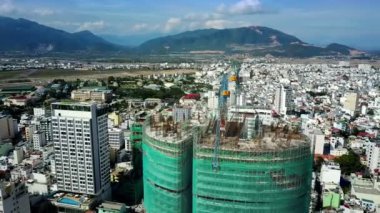 şehir ve uzak dağ karşı yeşil kafes üst görünüm zarar kasırga Vinçler bitmemiş binanın çatısında kaplı