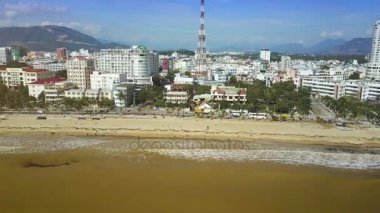 Panorama yüksek dalgalar sarı deniz plaj ve dağ karşı gökdelenler ile modern şehir çalıştırın ve mavi gökyüzü temizleyin