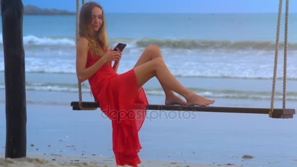 Menina Loira Bonita Vermelho Sundress Balança Banco Com Iphone Contra — Vídeo de Stock